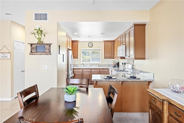 2802 Green River Rd Unit 101, Corona, CA 92882 - kitchen featuring white appliances, a peninsula, brown cabinetry, and a kitchen bar