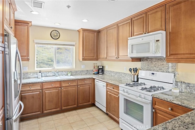 2802 Green River Rd Unit 101, Corona, CA 92882 - kitchen with white appliances, brown cabinets, light stone countertops, and recessed lighting