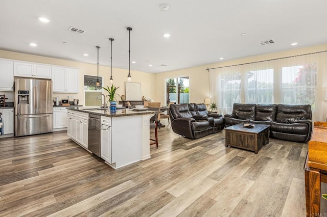 2910 Lucia Jade Loop, San Diego, CA 92139 - kitchen featuring appliances with stainless steel finishes, open floor plan, a breakfast bar area, wood finished floors, and white cabinets
