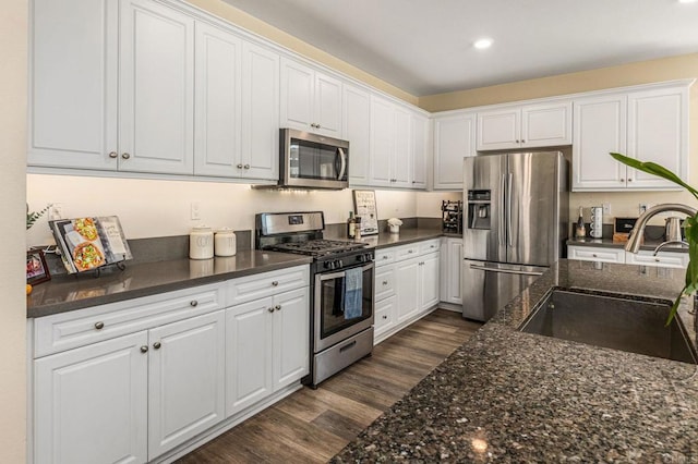 2910 Lucia Jade Loop, San Diego, CA 92139 - kitchen featuring appliances with stainless steel finishes, white cabinetry, dark wood-style floors, dark stone counters, and recessed lighting