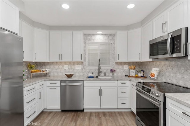 1837 N Studebaker Rd, Long Beach, CA 90815 - kitchen featuring stainless steel appliances, light wood finished floors, white cabinets, and decorative backsplash