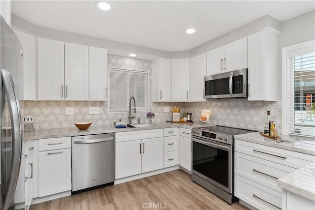 1837 N Studebaker Rd, Long Beach, CA 90815 - kitchen with appliances with stainless steel finishes, white cabinets, decorative backsplash, light stone countertops, and light wood-style flooring