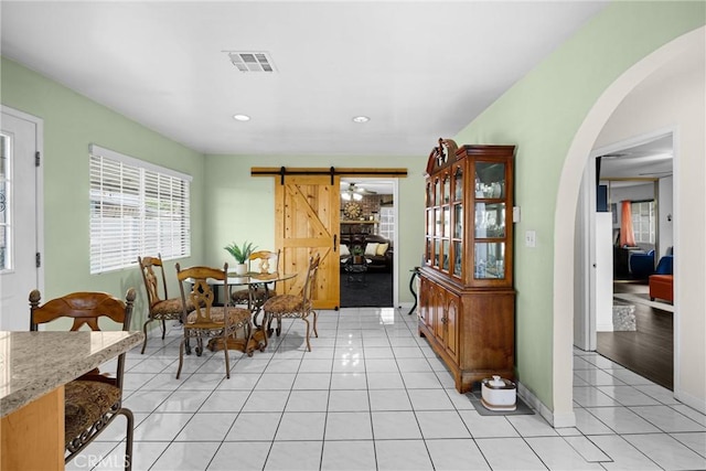 1320 Carob Way, Montebello, CA 90640 - dining space with light tile patterned floors, arched walkways, a barn door, and recessed lighting