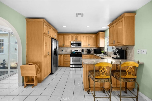 1320 Carob Way, Montebello, CA 90640 - kitchen with appliances with stainless steel finishes, arched walkways, a peninsula, tasteful backsplash, and recessed lighting