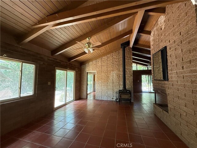 11955 Santa Lucia Rd, Atascadero, CA 93422 - unfurnished living room with a wood stove, dark tile patterned floors, high vaulted ceiling, a wood ceiling with exposed beams, and ceiling fan