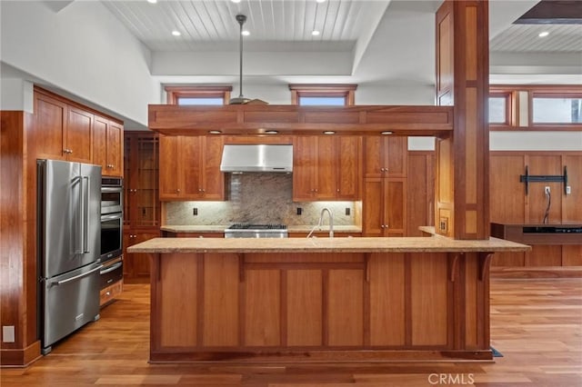 401 8th St, Manhattan Beach, CA 90266 - kitchen with appliances with stainless steel finishes, wall chimney range hood, brown cabinetry, light wood finished floors, and wooden ceiling