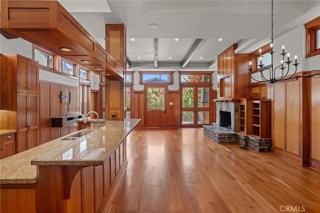 401 8th St, Manhattan Beach, CA 90266 - kitchen with brown cabinets, light wood-type flooring, a fireplace with raised hearth, wooden walls, and open floor plan