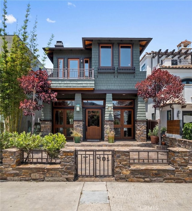 401 8th St, Manhattan Beach, CA 90266 - view of front of home with a balcony, a fenced front yard, stone siding, and a chimney