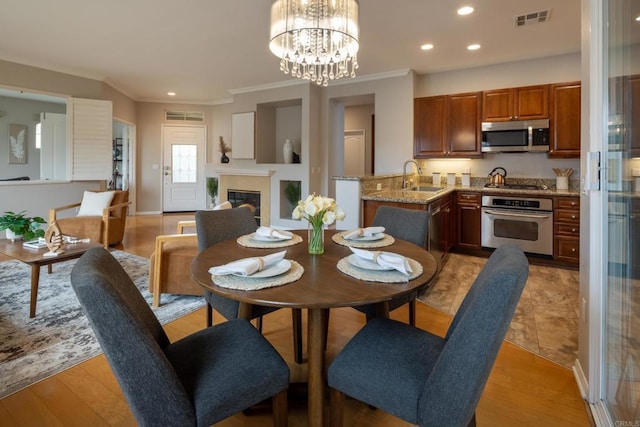 12625 Fiorenza Ln Unit 236, San Diego, CA 92128 - dining space featuring ornamental molding, recessed lighting, light wood-style floors, a glass covered fireplace, and a chandelier