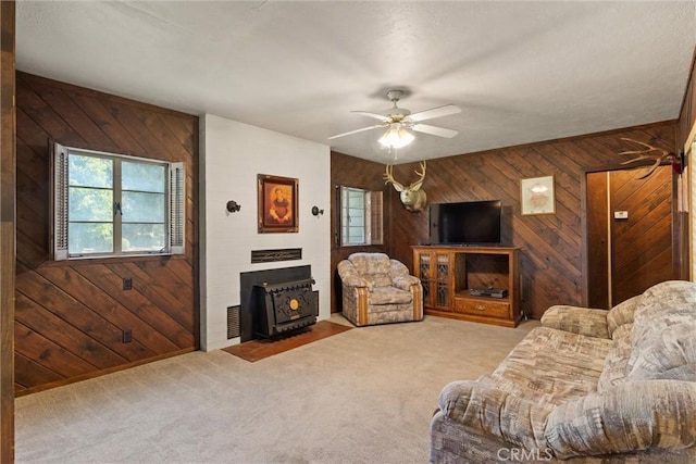 1603 Colusa St, Corning, CA 96021 - living area featuring a wood stove, wood walls, carpet floors, and a ceiling fan