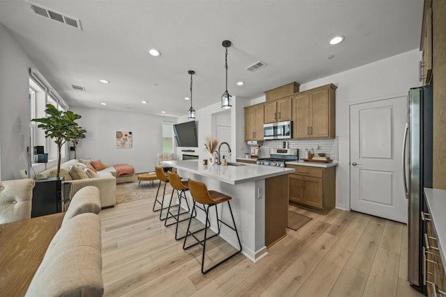 32755 Brunello Way, Temecula, CA 92591 - kitchen featuring stainless steel appliances, open floor plan, a breakfast bar area, light wood-style floors, and backsplash