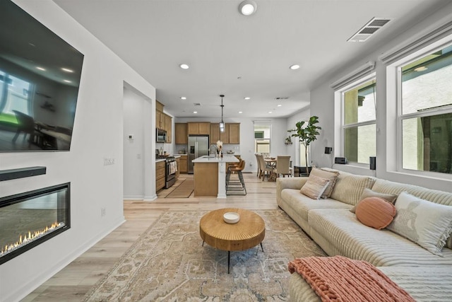32755 Brunello Way, Temecula, CA 92591 - living room featuring light wood-style flooring, recessed lighting, and a glass covered fireplace