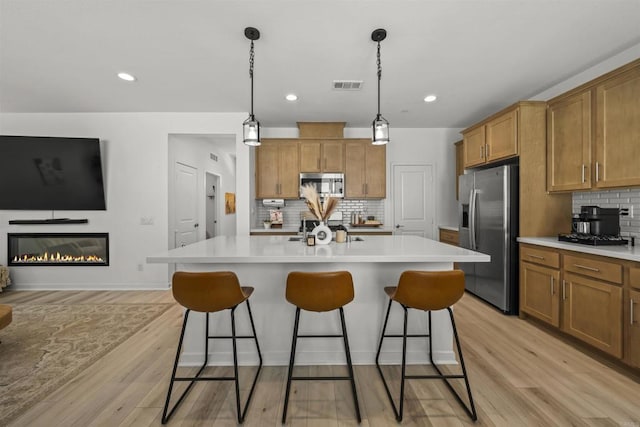 32755 Brunello Way, Temecula, CA 92591 - kitchen with appliances with stainless steel finishes, brown cabinets, decorative backsplash, a breakfast bar area, and recessed lighting