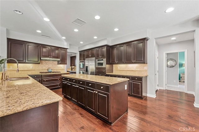 46379 Canyon Crest Ct, Temecula, CA 92592 - kitchen featuring appliances with stainless steel finishes, a center island, light stone counters, dark brown cabinets, and recessed lighting