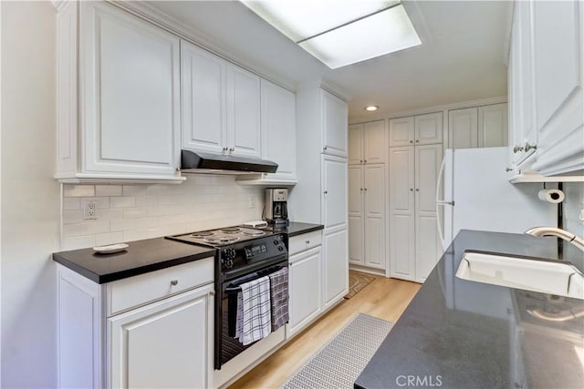3205 Via Buena Unit B, Laguna Woods, CA 92637 - kitchen with black / electric stove, under cabinet range hood, dark countertops, freestanding refrigerator, and recessed lighting