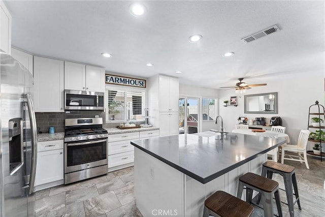 6057 Azalea St, Chino, CA 91710 - kitchen featuring stainless steel appliances, a breakfast bar, white cabinets, tasteful backsplash, and recessed lighting