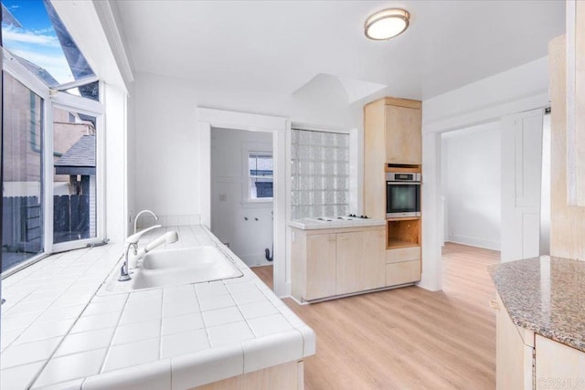 275 Euclid Ave, Long Beach, CA 90803 - kitchen featuring light brown cabinets, stainless steel oven, light wood-style flooring, tile counters, and healthy amount of natural light