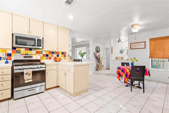 252 W Blaine St, Riverside, CA 92507 - kitchen featuring appliances with stainless steel finishes, cream cabinets, light countertops, a peninsula, and tasteful backsplash