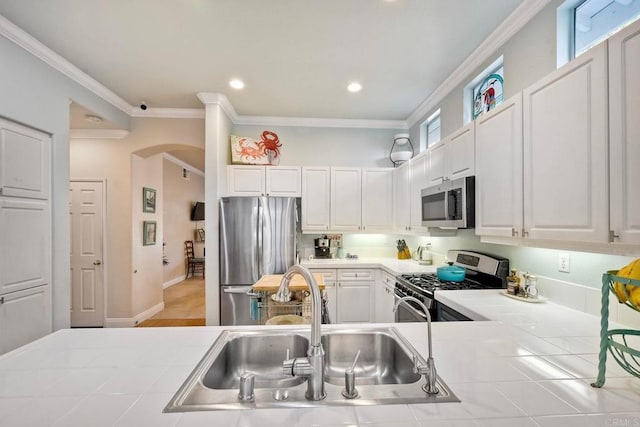 6707 Ketch Way, Carlsbad, CA 92011 - kitchen featuring appliances with stainless steel finishes, tile countertops, arched walkways, white cabinets, and ornamental molding