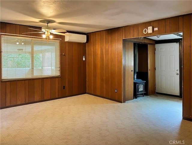 5128 W State Highway 20, Upper Lake, CA 95485 - empty room featuring a wall mounted AC, wooden walls, ceiling fan, a wood stove, and tile patterned floors