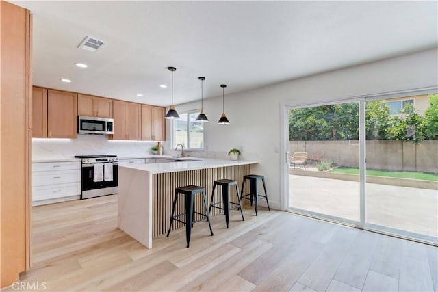 8312 Bellhaven St, La Palma, CA 90623 - kitchen featuring appliances with stainless steel finishes, light wood finished floors, a peninsula, light countertops, and a kitchen breakfast bar