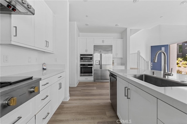 27216 W Coyote Bush Ct, Valencia, CA 91355 - kitchen featuring stainless steel appliances, ventilation hood, white cabinets, light wood finished floors, and light countertops