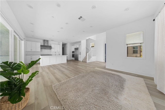 27216 W Coyote Bush Ct, Valencia, CA 91355 - unfurnished living room with light wood finished floors, healthy amount of natural light, and stairway