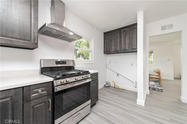 2058 N Pico Ave, San Bernardino, CA 92411 - kitchen featuring wall chimney exhaust hood, gas range, light countertops, dark brown cabinets, and light wood-type flooring