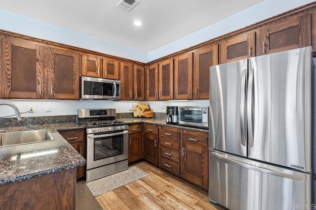 1527 Gold Run Rd, Chula Vista, CA 91913 - kitchen with stainless steel appliances, light wood-style flooring, dark stone counters, and recessed lighting