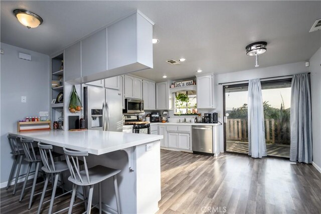 28521 Williams Dr, Menifee, CA 92587 - kitchen with stainless steel appliances, a peninsula, a breakfast bar area, light countertops, and light wood-style flooring