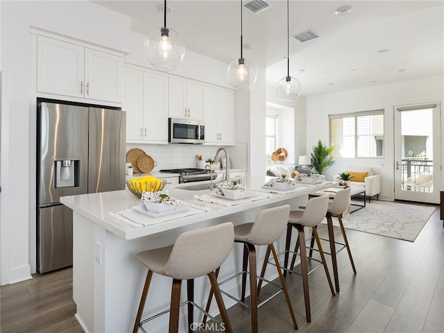 1673 Lexington Ln, San Pedro, CA 90732 - kitchen with stainless steel appliances, dark wood-style flooring, tasteful backsplash, a kitchen bar, and an island with sink