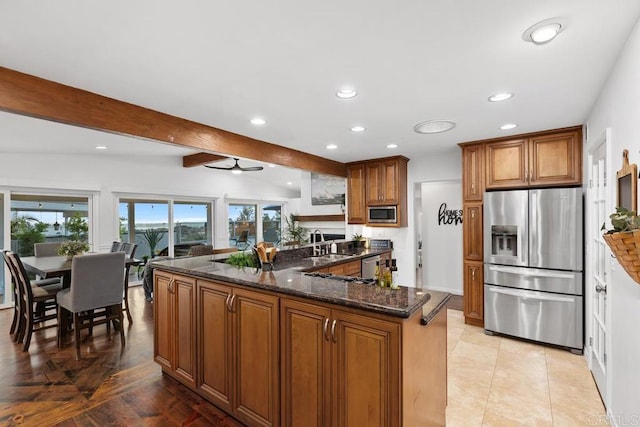 4704 Jumano Ave, San Diego, CA 92117 - kitchen featuring appliances with stainless steel finishes, brown cabinets, beam ceiling, dark stone countertops, and recessed lighting