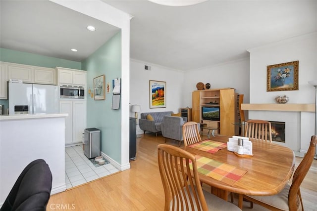 50 Los Cabos, Dana Point, CA 92629 - dining area featuring light wood-style floors, crown molding, a glass covered fireplace, and recessed lighting