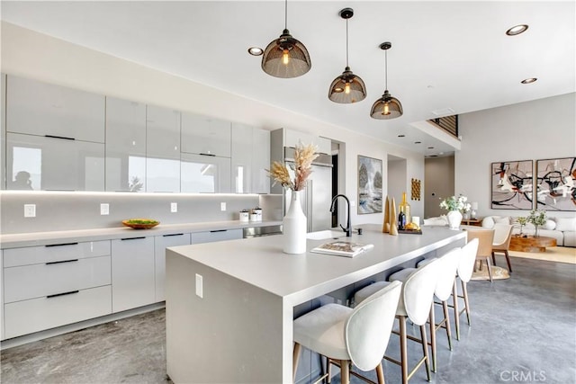 2380 Scenic Ridge Dr, Chino Hills, CA 91709 - kitchen featuring modern cabinets, concrete flooring, a center island with sink, light countertops, and a breakfast bar area