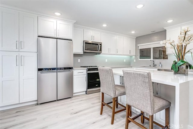 4014 Calle Sonora Oeste Unit 2B, Laguna Woods, CA 92637 - kitchen with stainless steel appliances, decorative backsplash, light countertops, white cabinetry, and a kitchen breakfast bar