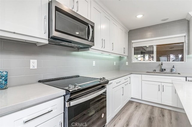 4014 Calle Sonora Oeste Unit 2B, Laguna Woods, CA 92637 - kitchen with stainless steel appliances, light countertops, tasteful backsplash, white cabinetry, and light wood-type flooring