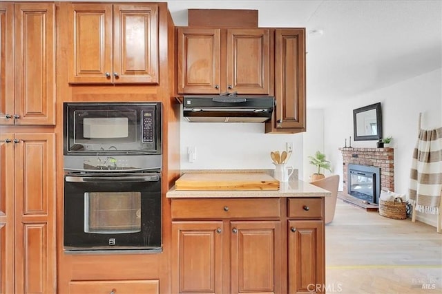 367 E Pacific Ave, Fairfield, CA 94533 - kitchen featuring black appliances, under cabinet range hood, a fireplace, wood finished floors, and light countertops