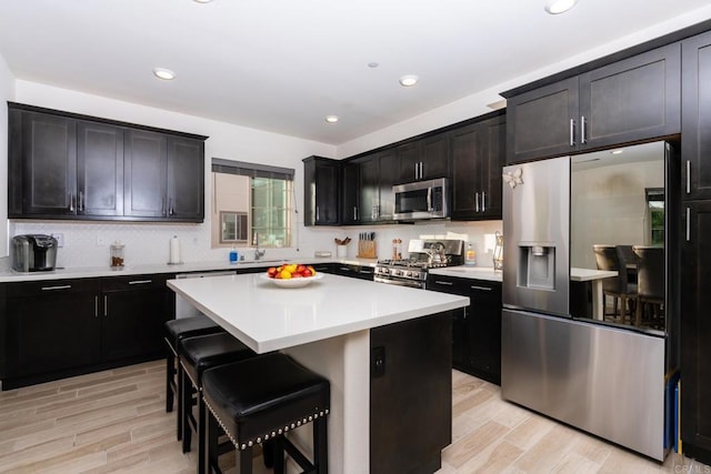 4336 Harbor Way Unit 1, Oceanside, CA 92056 - kitchen featuring appliances with stainless steel finishes, light wood finished floors, a kitchen breakfast bar, tasteful backsplash, and a kitchen island