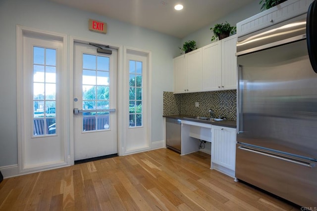 4336 Harbor Way Unit 1, Oceanside, CA 92056 - kitchen with stainless steel appliances, dark countertops, light wood finished floors, white cabinets, and decorative backsplash