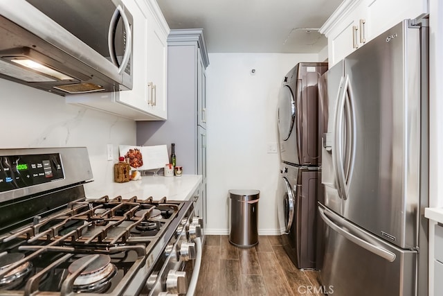 240 Nice Ln Unit 114, Newport Beach, CA 92663 - kitchen with stainless steel appliances, stacked washer / drying machine, dark wood finished floors, light countertops, and white cabinets