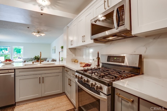 240 Nice Ln Unit 114, Newport Beach, CA 92663 - kitchen with appliances with stainless steel finishes, decorative backsplash, white cabinets, gray cabinets, and open floor plan