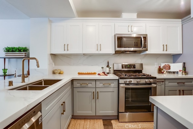 240 Nice Ln Unit 114, Newport Beach, CA 92663 - kitchen with appliances with stainless steel finishes, gray cabinets, white cabinets, light wood-style floors, and light stone counters