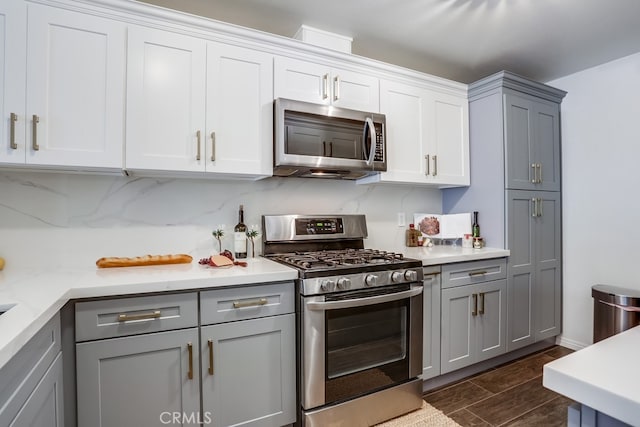 240 Nice Ln Unit 114, Newport Beach, CA 92663 - kitchen with stainless steel appliances, gray cabinetry, light countertops, dark wood-style floors, and white cabinets
