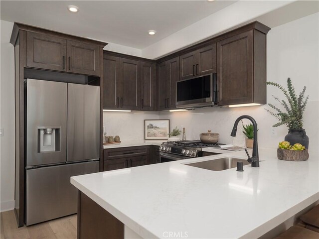 402 W Grand Ave Unit 101, Grover Beach, CA 93433 - kitchen featuring appliances with stainless steel finishes, a peninsula, dark brown cabinetry, light countertops, and recessed lighting