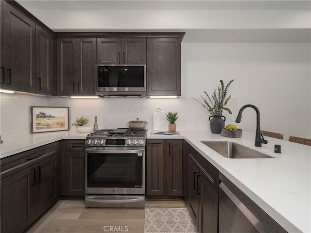 402 W Grand Ave Unit 101, Grover Beach, CA 93433 - kitchen with appliances with stainless steel finishes, dark brown cabinets, light countertops, light wood-style flooring, and a peninsula