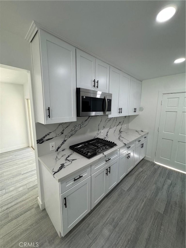 5230 Seville Ave, Encino, CA 91436 - kitchen with appliances with stainless steel finishes, white cabinets, wood finished floors, tasteful backsplash, and light stone counters