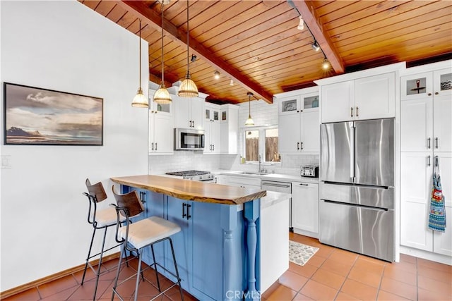 24932 La Cresta Dr, Dana Point, CA 92629 - kitchen with appliances with stainless steel finishes, track lighting, a wooden ceiling with exposed beams, light tile patterned floors, and a peninsula