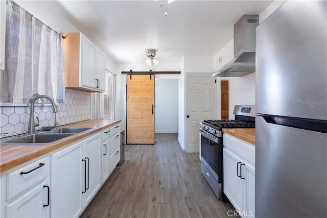 15508 Elmcroft Ave, Norwalk, CA 90650 - kitchen featuring appliances with stainless steel finishes, butcher block countertops, wall chimney range hood, a barn door, and tasteful backsplash