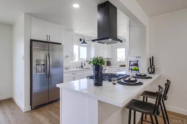 2451 Helix St, Spring Valley, CA 91977 - kitchen featuring stainless steel appliances, island exhaust hood, a peninsula, a breakfast bar, and light wood-style floors