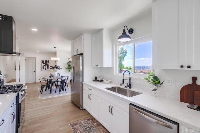 2451 Helix St, Spring Valley, CA 91977 - kitchen with stainless steel appliances, wall chimney exhaust hood, white cabinetry, light countertops, and light wood-type flooring